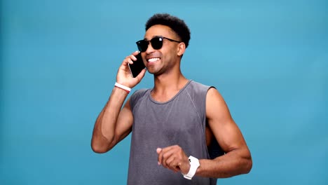 Young-smiling-african-man-talking-by-phone-over-blue-background.