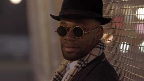 Young-Man-with-African-American-Ethnicity-Wearing-Old-Classic-Look.-Having-Fun-in-the-Big-City-with-Sunglasses,-Hat-and-Scarf.