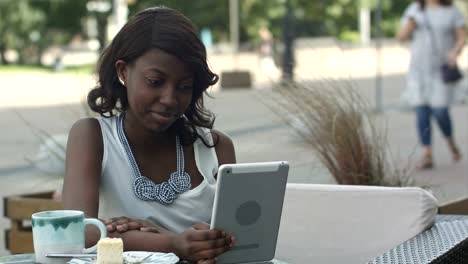 Afroamerikanische-Frau-haben-video-Konferenz-auf-ihr-Tablet-im-außen-Café-sitzen