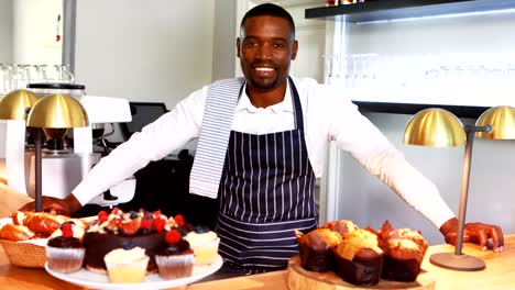 Portrait-of-smiling-waiter-standing-counter