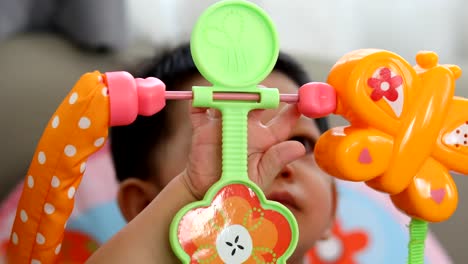 niedliche-Baby-Boy-mit-Finger-Hand-spielen,-bunten-Spielzeug-hängen-oben-im-Kinderzimmer