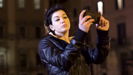 Charming-brunette-shoots-funny-selfie,-city-nights-in-the-background