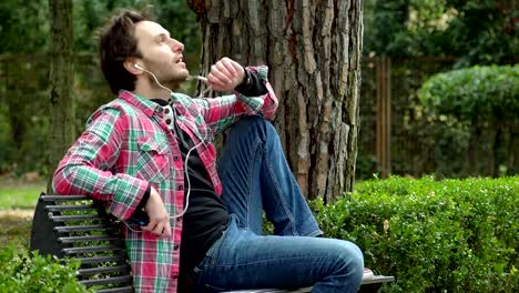 relaxed-man-in-the-park,-talking-on-the-phone-with-earphones