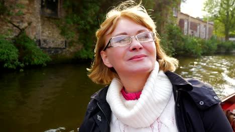 Woman-floating-on-a-boat-traveling-through-the-canal-of-the-ancient-city.