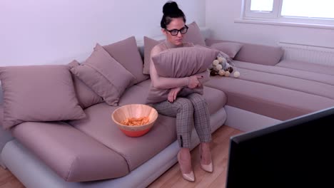 Woman-using-TV-remote-control-and-keeping-bowl-with-chips