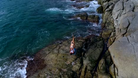 Antenne:-Acro-Yoga-auf-den-Felsen-nahe-dem-Meer-und-schönen-Wellen.