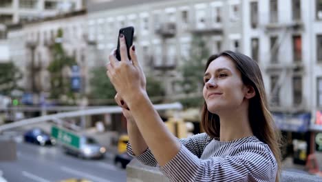 Junge-schöne-Frau-Selfie-fotografieren-auf-Smartphone.-Befahrenen-Straße-und-beschäftigt-Stadtbild-auf-dem-Hintergrund