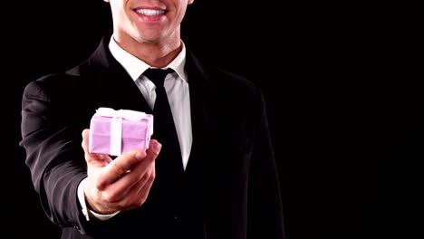 A-close-up-of-how-a-guy-stretches-out-his-hand-with-a-small-gift-box