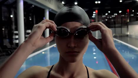 Nadador-de-cara-mujer-quitarse-gafas-en-la-piscina-de-agua-y-mirando-en-cámara