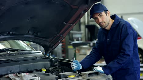 Specialist-auto-mechanic-in-the-car-service,-checks-the-car,-engine,-engine,-carburetor.-Concept:-repair-of-machines,-fault-diagnosis,-repair-specialist,-technical-maintenance-and-on-board-computer.