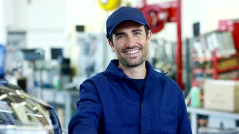 Retrato-de-un-joven-mecánico-hermosa-en-un-taller-de-coches,-en-el-fondo-del-servicio.-Concepto:-reparación-de-máquinas,-diagnóstico-de-fallas,-reparación-especialista,-mantenimiento-técnico-y-ordenador-de-a-bordo