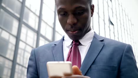 young-black-businessman-in-the-street-types-on-his-smartphone