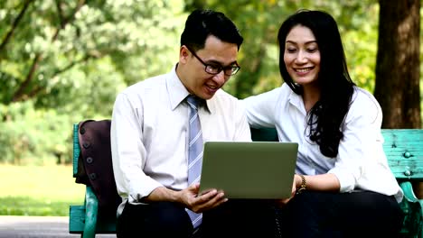 Happy-business-people-are-sitting,-talking,-meeting,-discussing-and-working-with-laptop-in-the-park.