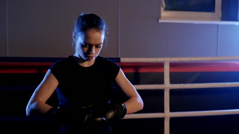 Mujer-hermosa-kickboxing-guantes-de-boxeo-de-ajustar-y-limpiar-el-sudor-en-el-gimnasio.