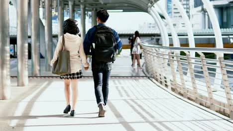 Behind-young-couple-holding-hands-and-walking-together