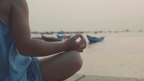 Little-cute-girl-meditates-in-turkish-pose-at-seafront