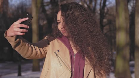 Medium-erschossen-von-einer-schönen-jungen-Frau,-die-unter-einem-Selfie-am-Stadtpark