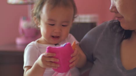 A-toddler-being-held-by-her-mother-gives-her-stuffed-animal-hugs