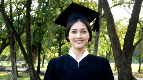 Jóvenes-estudiantes-mujer-Asia-usando-graduación-sombrero-y-vestido,-fondo-del-jardín,-mujer-con-el-concepto-de-graduación.