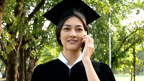 Jóvenes-estudiantes-mujer-asiática-con-Smartphone-para-hablar-con-amigo-en-el-parque,-fondo-jardin,-mujer-con-el-concepto-de-graduación.