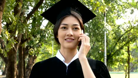 Junge-asiatische-Frau-Schüler-mit-Smartphone-für-Gespräch-mit-Freund-im-Park,-Garten-Hintergrund,-Frau-mit-Graduierung-Konzept.