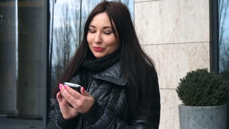 Mujer-hermosa-de-raza-mixta-con-aplicación-de-tecnología-de-teléfono-inteligente-caminando-por-las-calles-urbanas-feliz