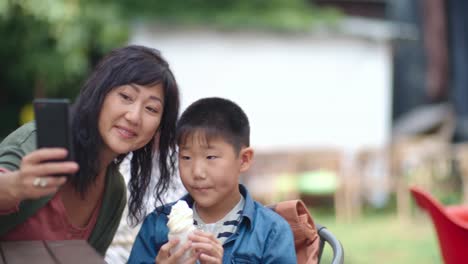 Mom-and-Child-Taking-Picture-with-Smartphone-in-Cafe-Outdoors