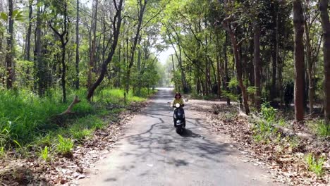 Young-lady-funny-riding-a-scooter--on-a-country-road.