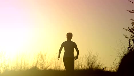 Junge-sportliche-Frau-läuft-im-Freien-bei-Sonnenuntergang-in-Berglandschaft.