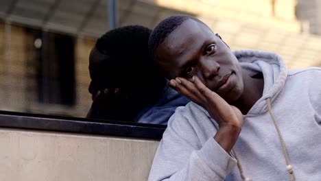 Pensive-Black-american-young-man-in-the-street,-looking-at-camera