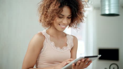 Smiling-happy-Afro-American-woman-using-pc-tablet-at-home.