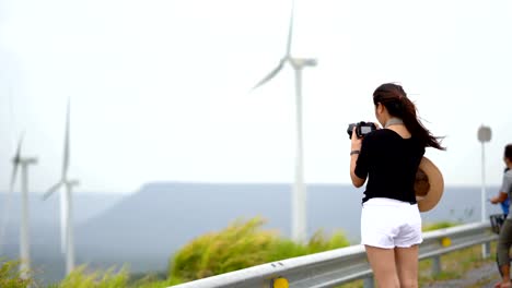 Asiatische-Frauen-Touristen-nehmen-ein-Bild-von-einer-Windkraftanlage-in-eine-landschaftlich-reizvolle-Ort.