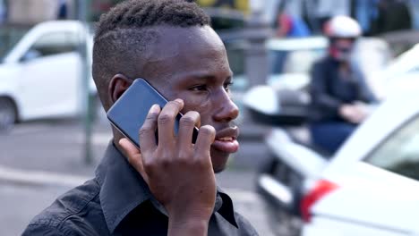 Young-american--african-man-talking-by-phone-in-the-street--profile