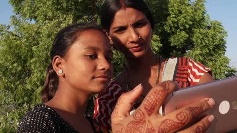 Mujeres-riendo-sonriendo-tomando-selfie-video-foto-junto-con-un-medio-de-ayudar-a-mano-teléfono-inteligente-dispositivo-ayudar-a-tiro-dos