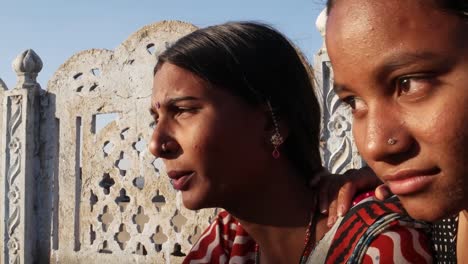 Dos-mujeres-vinculación-hablar-compartir-estar-mirando-en-el-mismo-lugar-perfil-lateral-en-una-terraza-en-vestido-tradicional-en-India-mano-dos-amor-tiro-medio-tradición-rural-al-aire-libre-calor-sol-de-verano