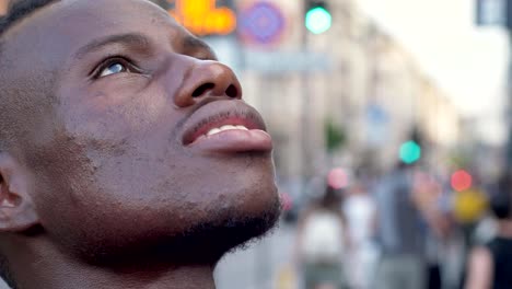 Smiling-young-black-man-in-the-city-looking-up--slow-motion