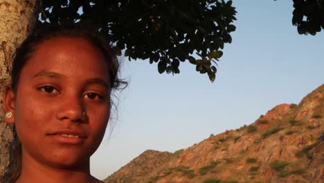 Adolescente-India-hermosa-chica-viendo-en-una-cima-de-la-colina-debajo-de-un-árbol-en-un-día-de-verano-de-amor-impaciente-alegría-feliz-sol-tropical-caliente-brillante-sol-contenido-mirando-a-cámara-handheld-estabilizado