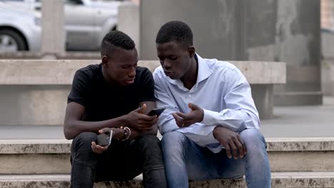 young-black-African-friends-talking-with-cellphones-in-hands---outdoor