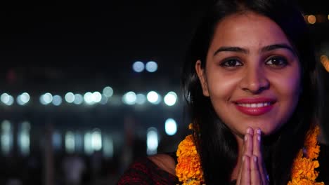 Beautiful-young-woman-hands-joined-in-namaste-greets-with-orange-marigold-flower-garland-on-her-neck-offers-prayers-worship-God-Goddess-hands-welcomes-smiles-glowing-respect-believer-religion-handheld