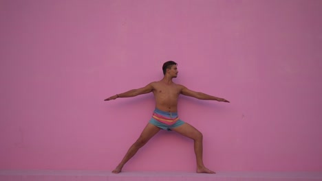 Mixed-race-hispanic-young-man-with-naked-torso-practicing-yoga-fitness-exercise-on-pink-background.-Sport,-meditation-and-lifestyle-concept.-Peaceful-Meditation-for-good-health