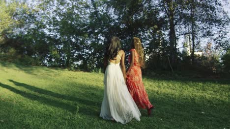 Lenta-de-dos-mujeres-llevando-vestidos-y-caminando-en-un-hermoso-parque