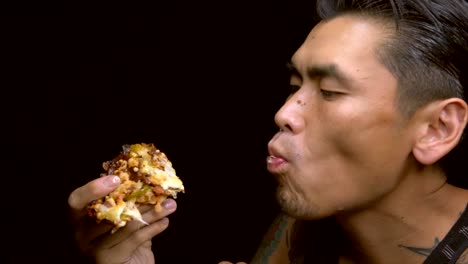 asian-tattooed-man-voraciously-eats-a-slice-of-pizza