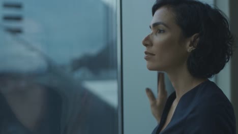 Close-up-Portrait-of-the-Beautiful-Young-Businesswoman-Looking-Thoughtfully-out-of-Her-Office-Window-with-Cityscape-View.-Confident-and-Attractive-Hispanic-Woman-Thinking-about-Her-Business-Project.