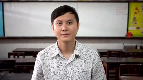 Portrait-of-young-handsome-Asian-male-teacher-smiling-inside-the-classroom