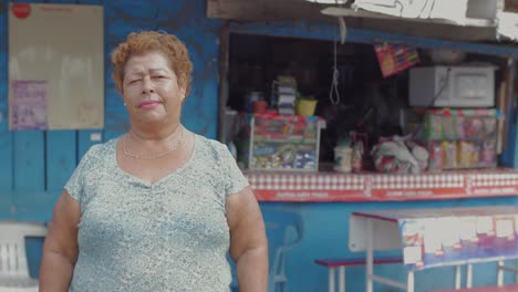 Eine-große-Porträt-einer-älteren-hispanic-Frau-Blick-auf-die-Kamera-stehend-vor-einem-Imbiss-Stand-in-Mexiko