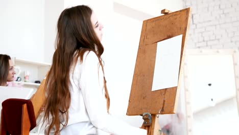 Young-attractive-woman-sits-behind-the-easel