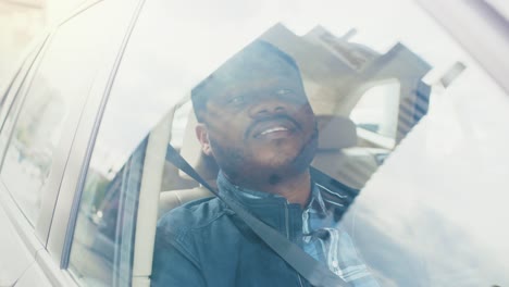 Hübscher-junger-schwarzer-Mann-reitet-auf-dem-Beifahrersitz-eines-Autos,-schaut-aus-dem-Fenster.-Blick-auf-die-große-Stadt-spiegelt-sich-im-Fenster.-Kamera-Auto-außen-bewegen.