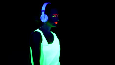 Woman-with-UV-paint,-glowing-bracelet,-clothing-dancing-and-listening-to-music-with-headphones.-Caucasian-woman.-.