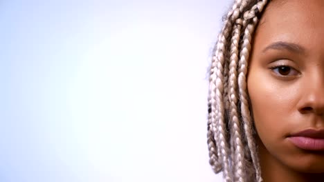 Half-face-of-young-African-girl-with-dreadlocks-looking-at-camera,-serious-face,-white-background.