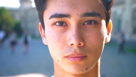 Close-up-Portrait-von-asiatischen-männlichen-Blick-in-die-Kamera-gerade,-schwere-konzentrierte-Stimmung-im-Schatten,-im-Sommer-im-freien